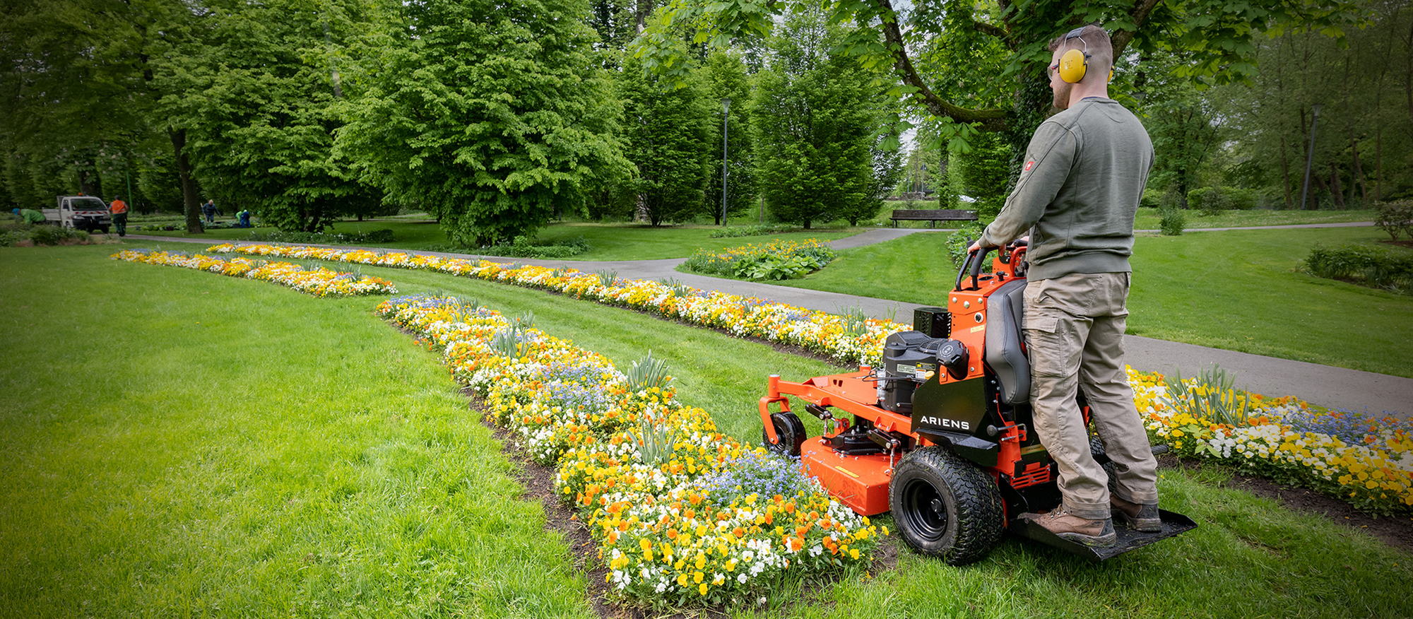 Mann mäht Wiese mit Ariens Arrow Stand-On-Mäher, stehend auf der integrierten Plattform.