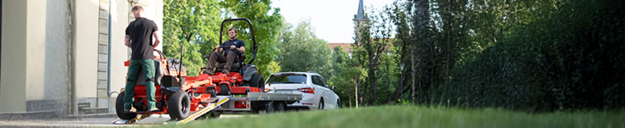 Zwei Männer entladen Ariens Zero-Turn-Mäher von einem Anhänger.