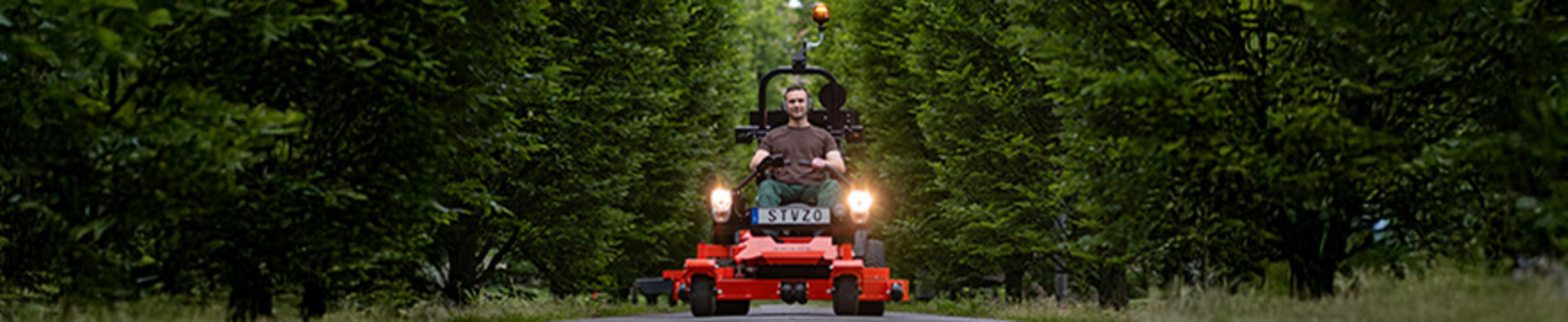 Ariens Zero-Turn-Mäher mit montiertem Straßen-Kit fährt auf Straße durch eine Allee